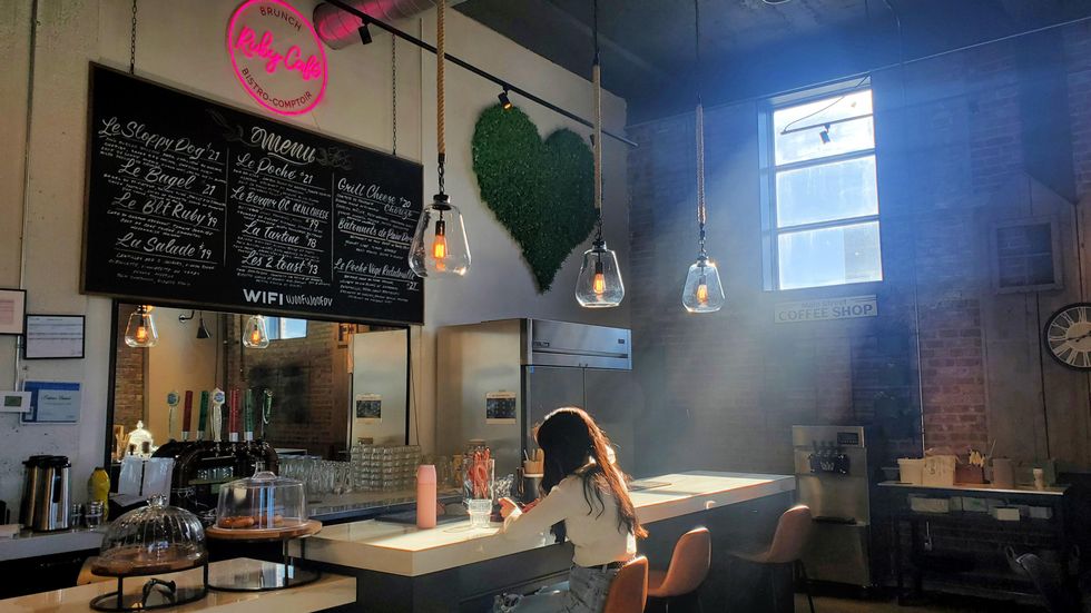 Someone sits at the bar under a window flooding the cafe with natural light.