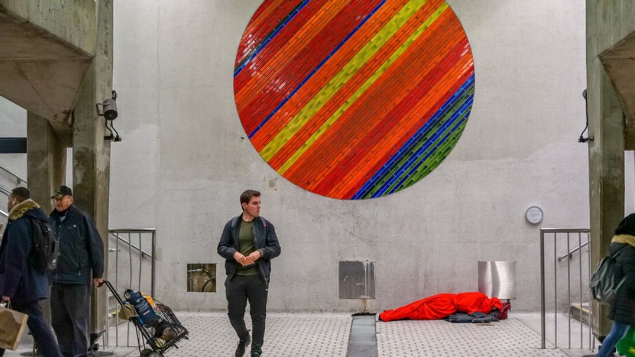 Someone sleeping under art in a Montreal metro station.