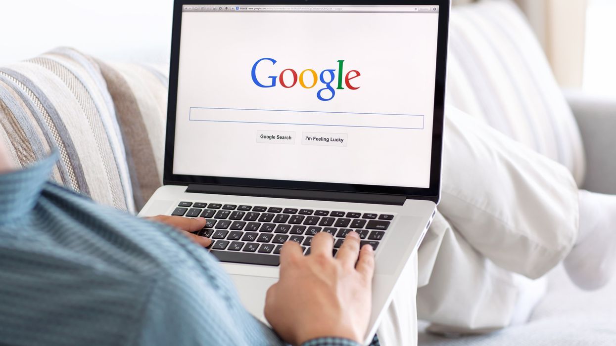 Someone using a laptop on the Google search page.