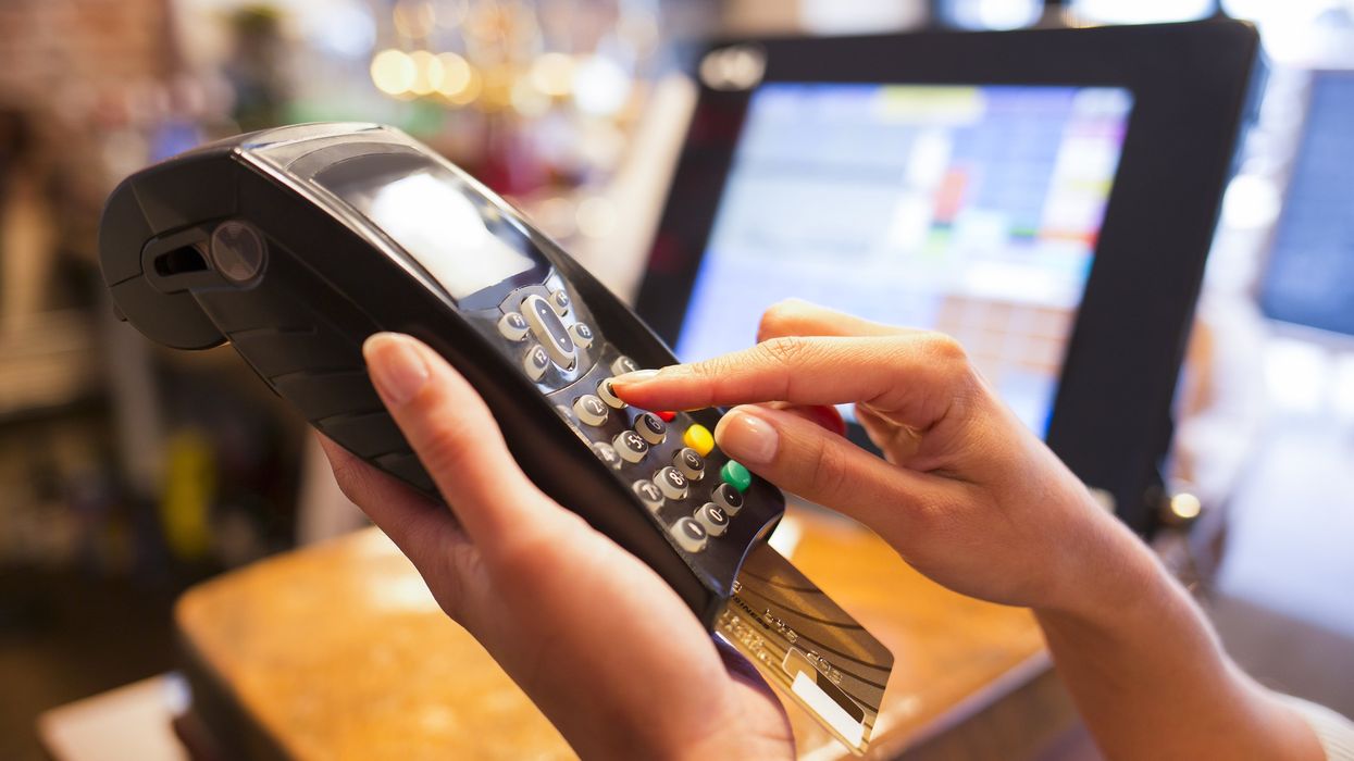 Someone using a payment terminal in a cafe (illustrative).