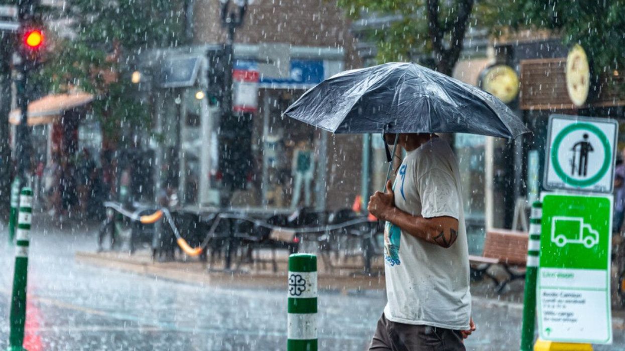 Someone walks down Mont-Royal holding an umbrella during a storm.