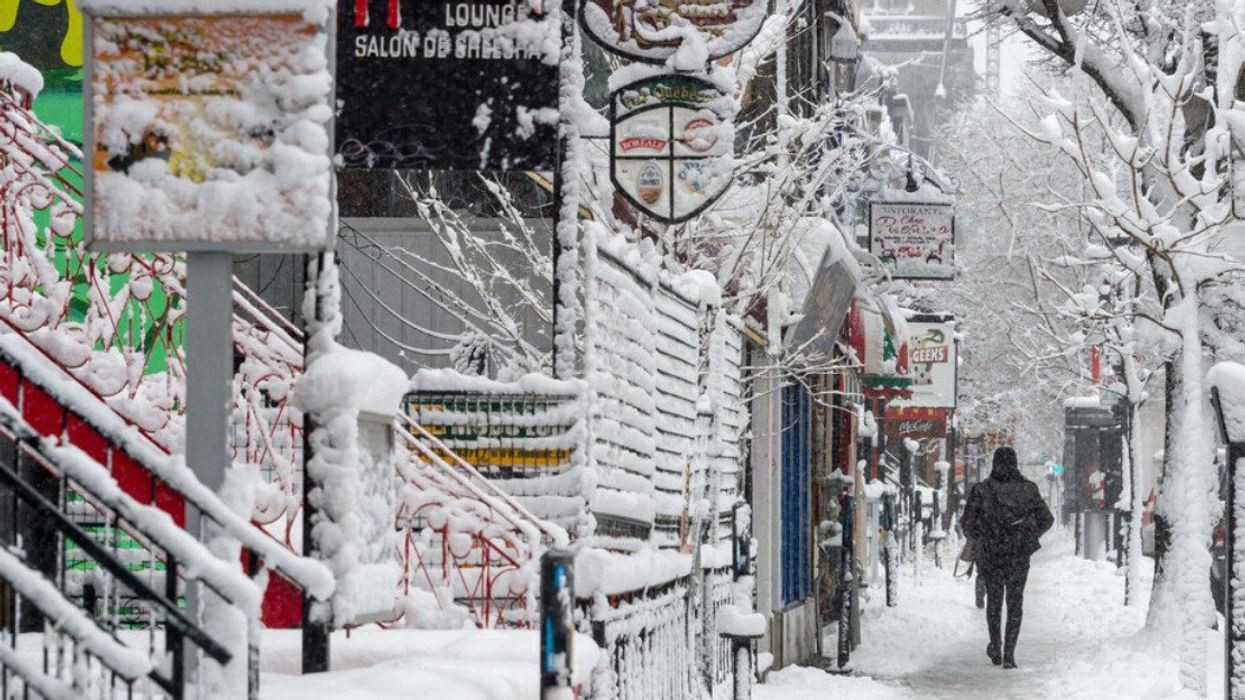 Someone walks down rue Saint Denis during a snowstorm.