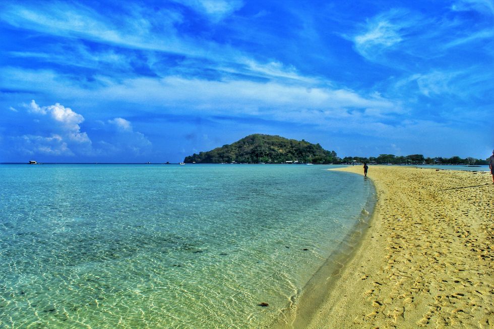Someone walks on the pristine shore of Bawean Island.