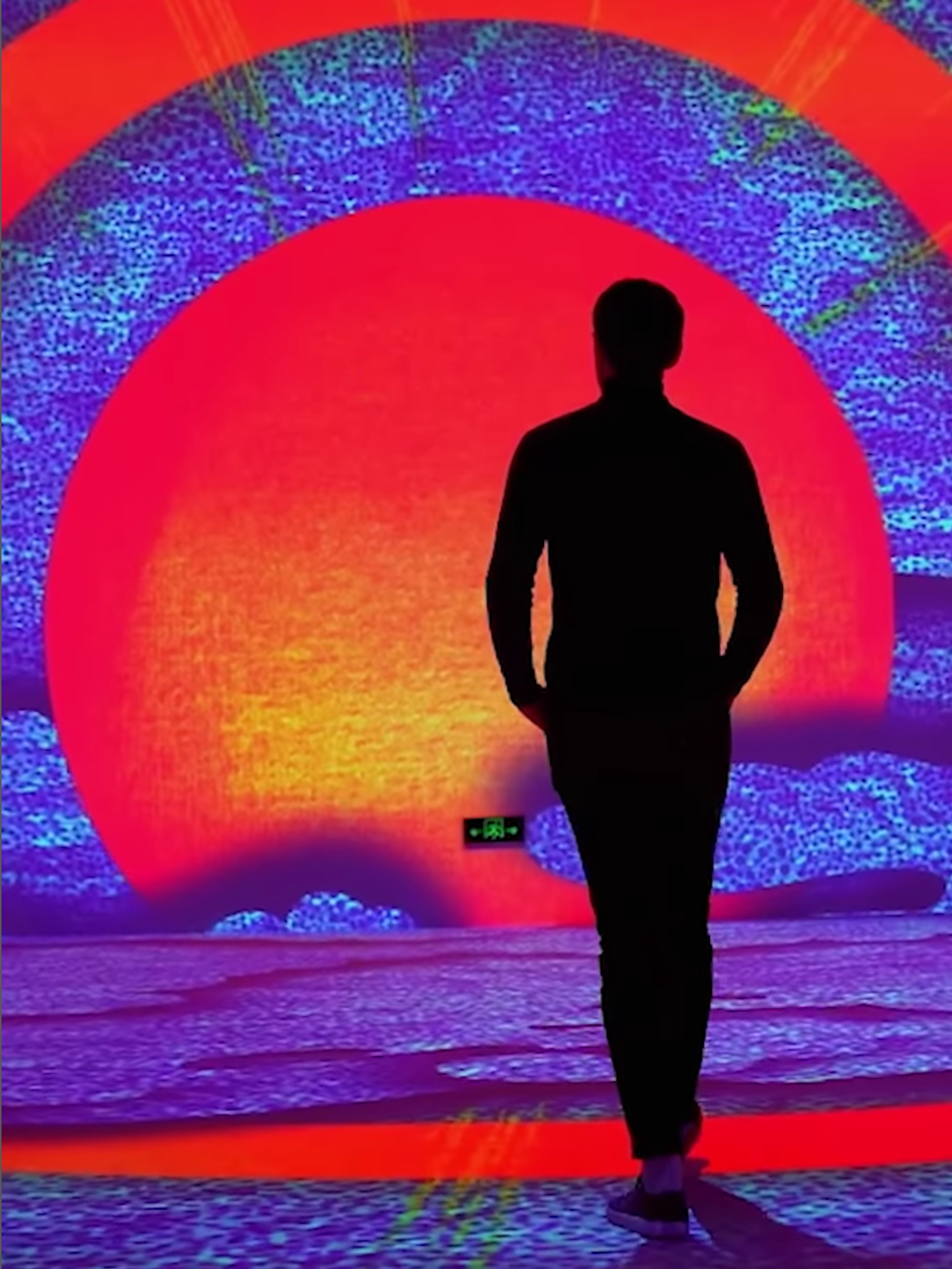 Someone walks through projections of a sun and clouds.