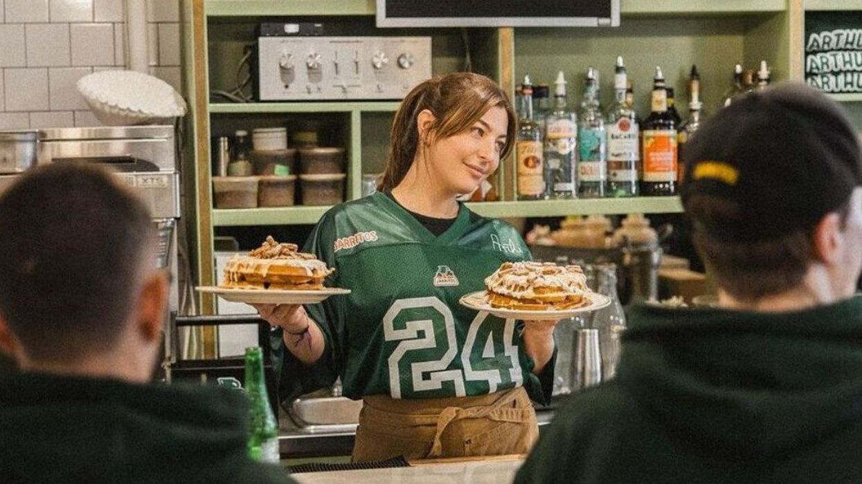 Someone wearing a green jersey holds up plates of waffles.