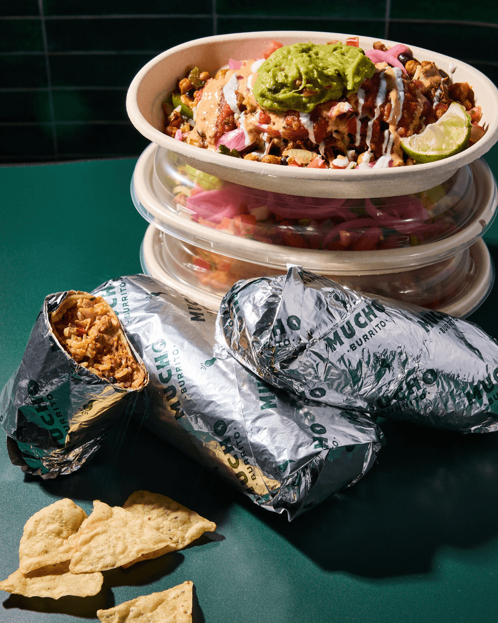 Stacked burrito bowls and burritos wrapped in foil