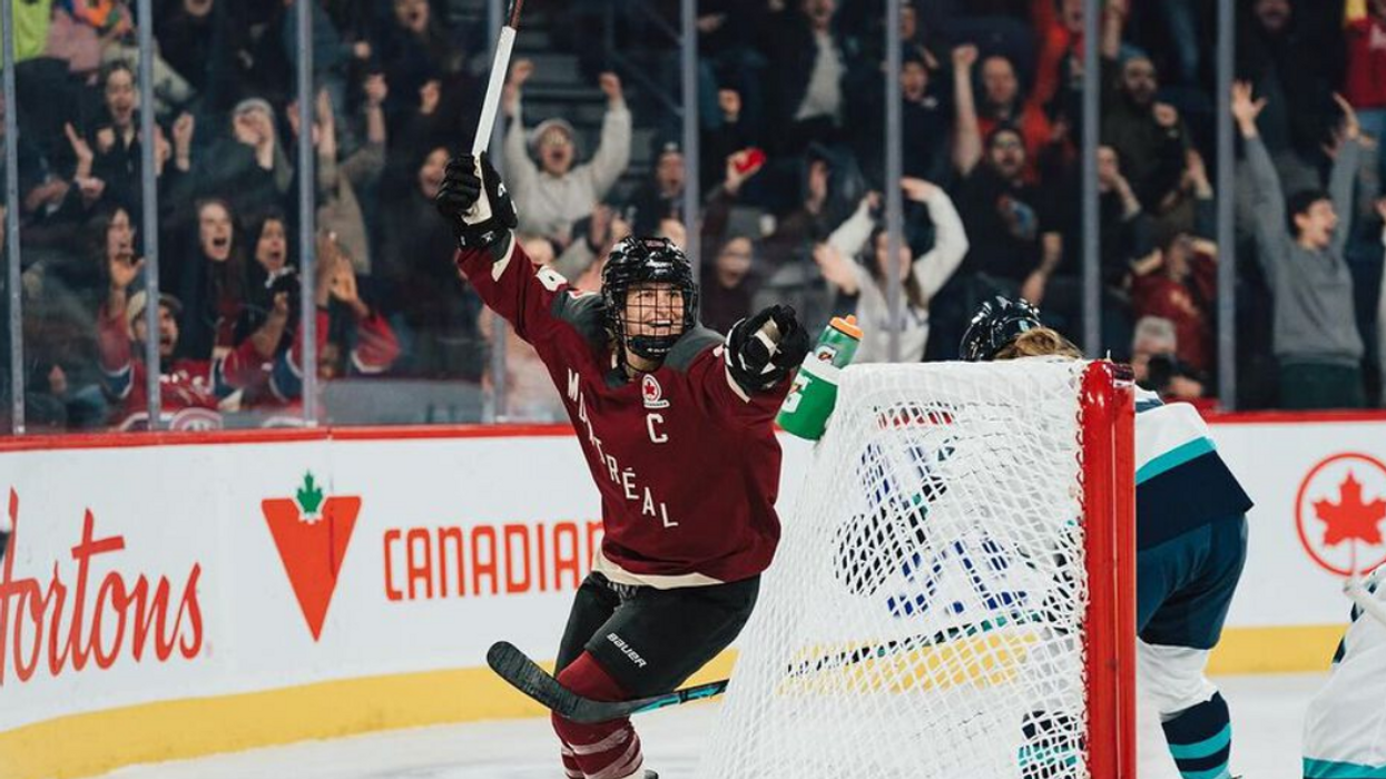 Team captain, Marie-Philip Poulin, raises her arms in victory after a goal.