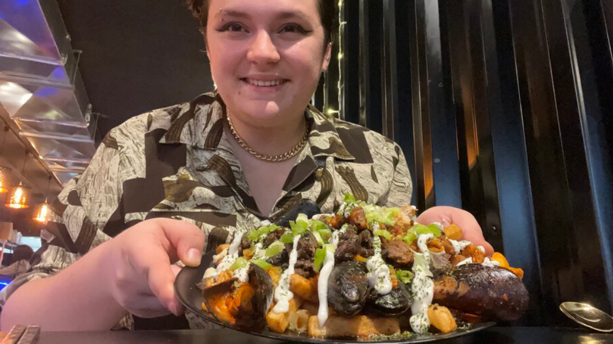 The author holding a plate of very loaded poutine.