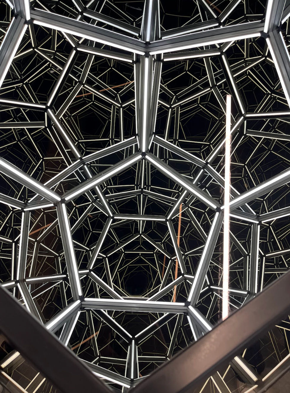The camera peers into a seemingly endless space made of mirrors and lights.
