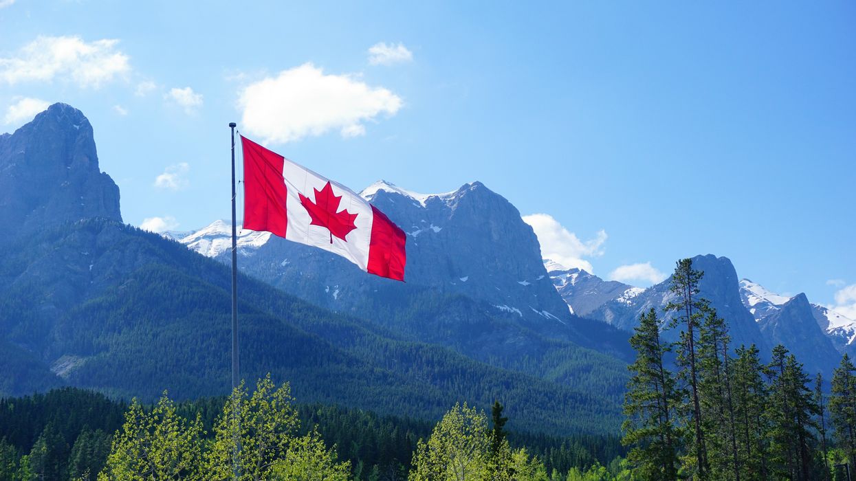 The Canada flag flying with mountains in the background.