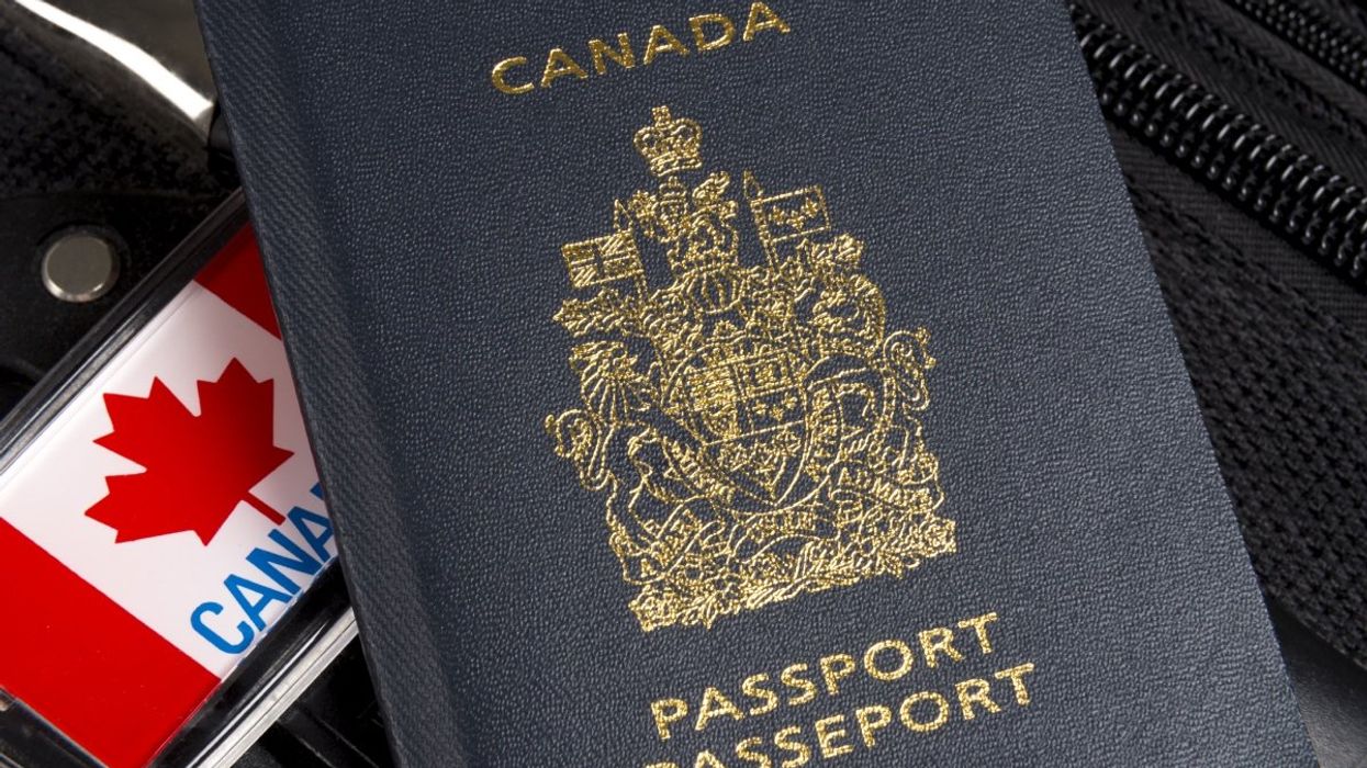The Canadian passport atop a luggage with a Canada flag souvenir beside it.