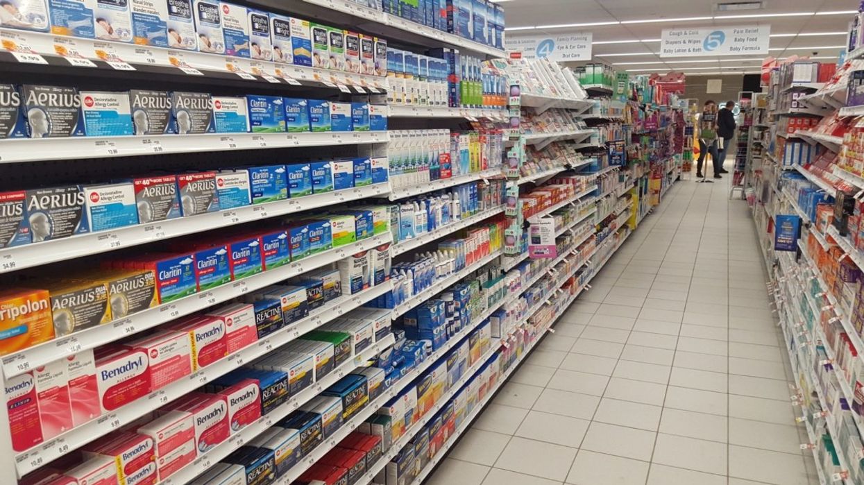 The cold and flu medication aisle at a Shoppers Drug Mart in Canada with various brands of medication on shelves.