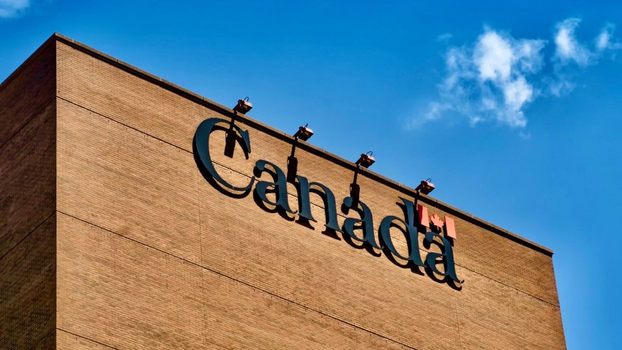 The exterior of a Canada Revenue Agency building with the Canada logo and Canadian flag attached to the brown brick wall.