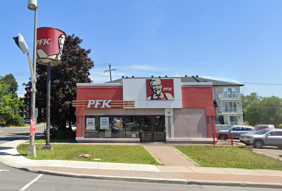 The exterior of a KFC restaurant off of a busy road.