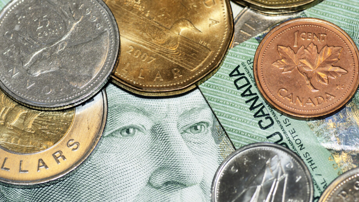 The former Queen's face peeks out from under a pile of Canadian coins and bills.