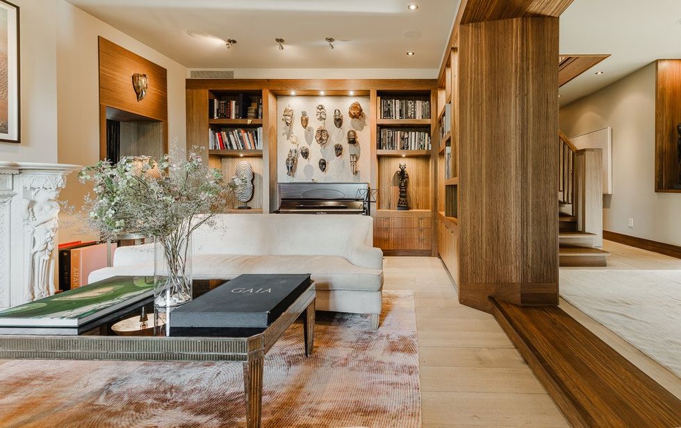 The living room with a carved fireplace and wall of masks.