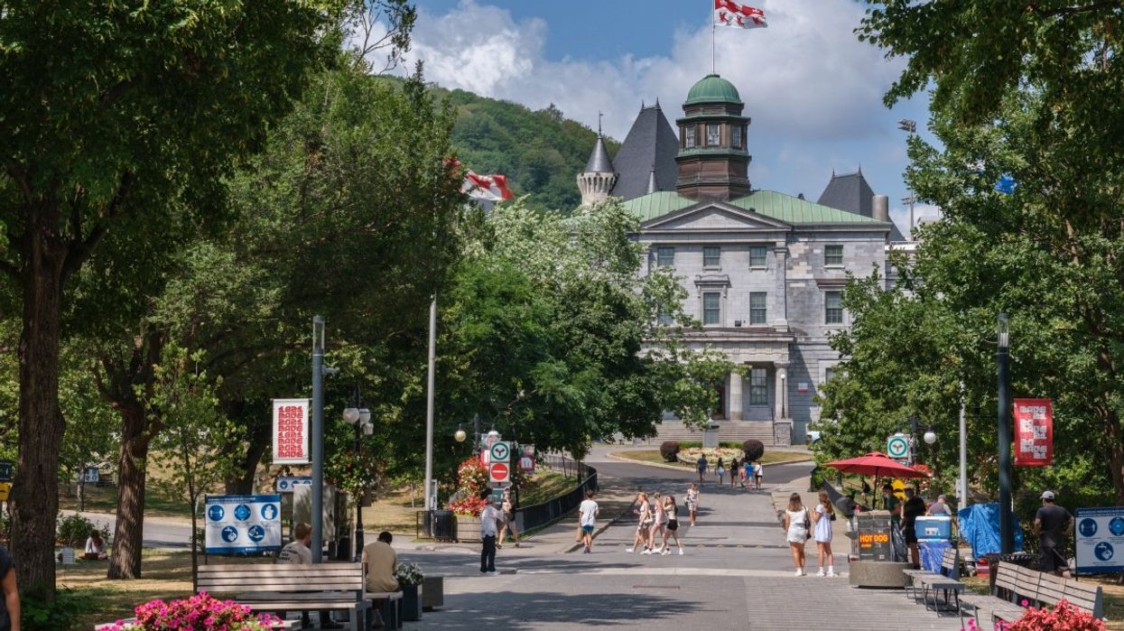 The McGill University main building during the summer with several people walking by.