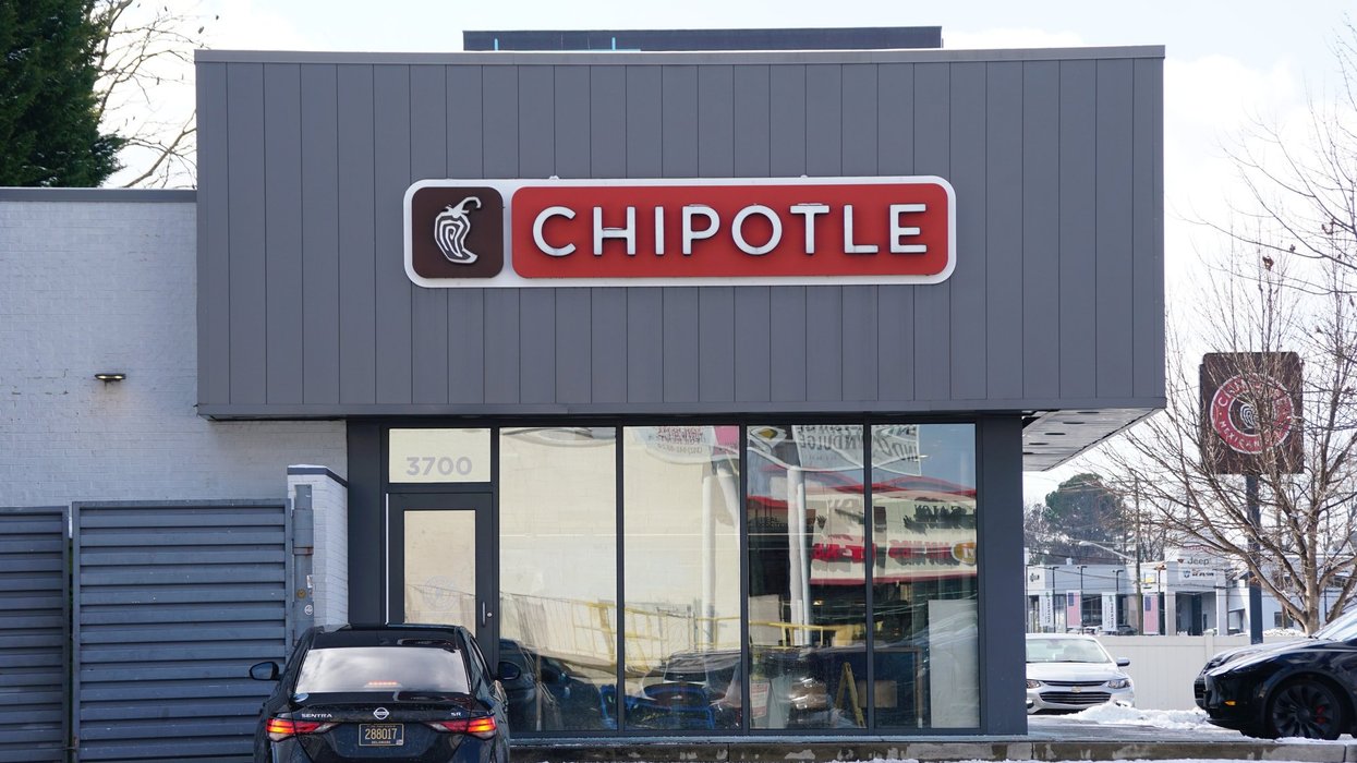 The modern exterior of a Chipotle Mexican Grill features a grey facade and a black car parked in front.