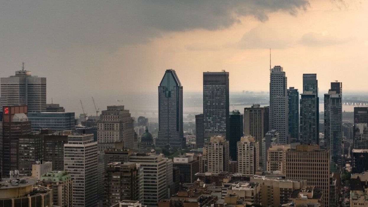 The Montreal skyline under clouds on one side and sunny skies on the other.