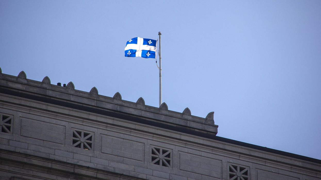 The Quebec flag flies over an old office building in Montreal.