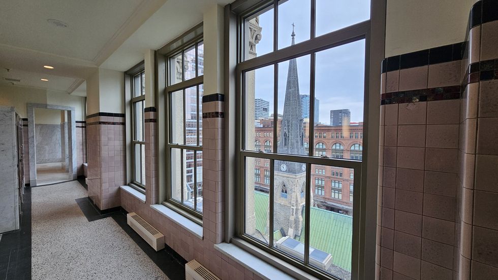 Three windows between striped pink tile walls overlook a church with a bright green roof.