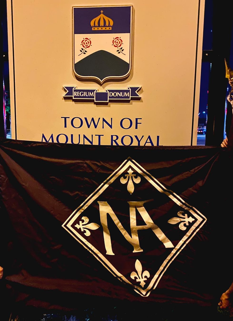 Town of Mount Royal sign partly covered by Nouvelle Alliance's flag.
