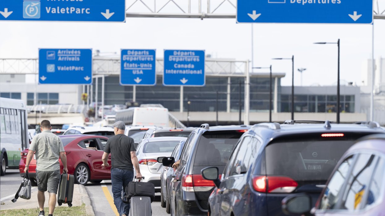 Travellers walk through traffic with their luggage at Montreal airport.