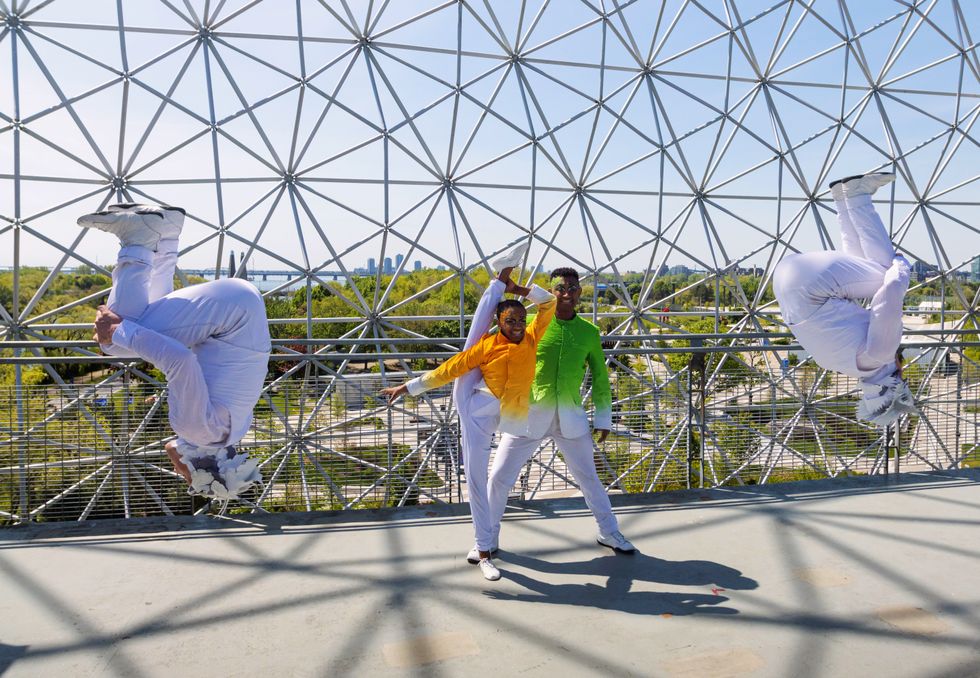Two acrobats flip in the air, while others hold an extreme pose.