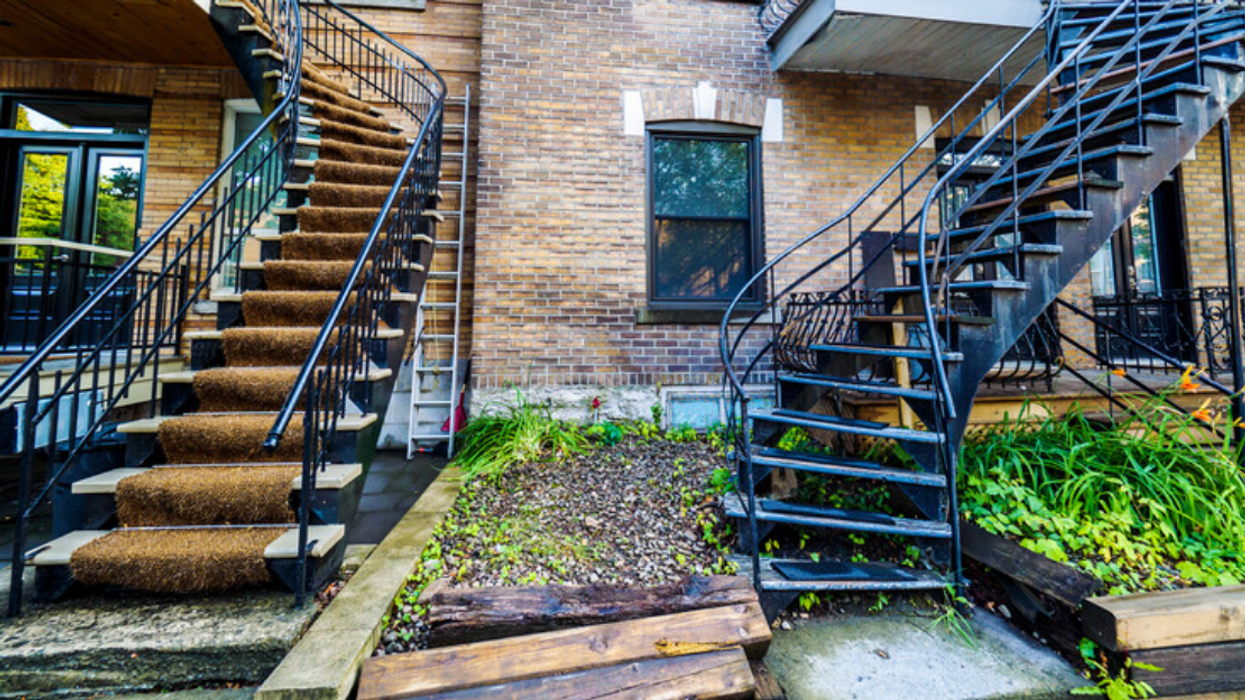 Two exterior iron staircases in front of homes on a typical Montreal street.