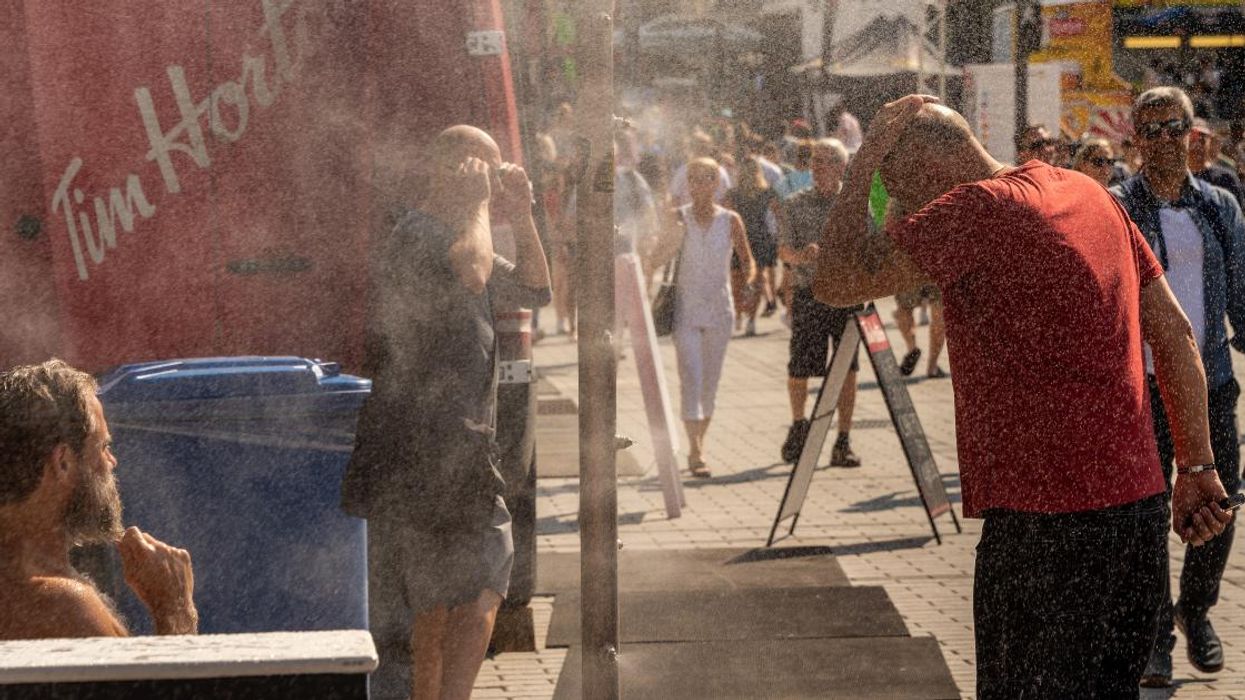 Two people cooling off at a misting station in Montreal.