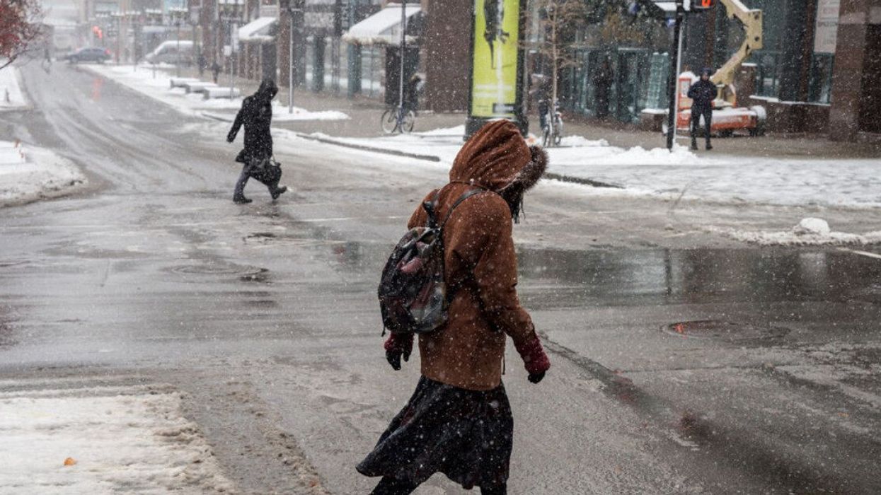 Two people cross McGill College in Montreal during the first snowfall of the season.