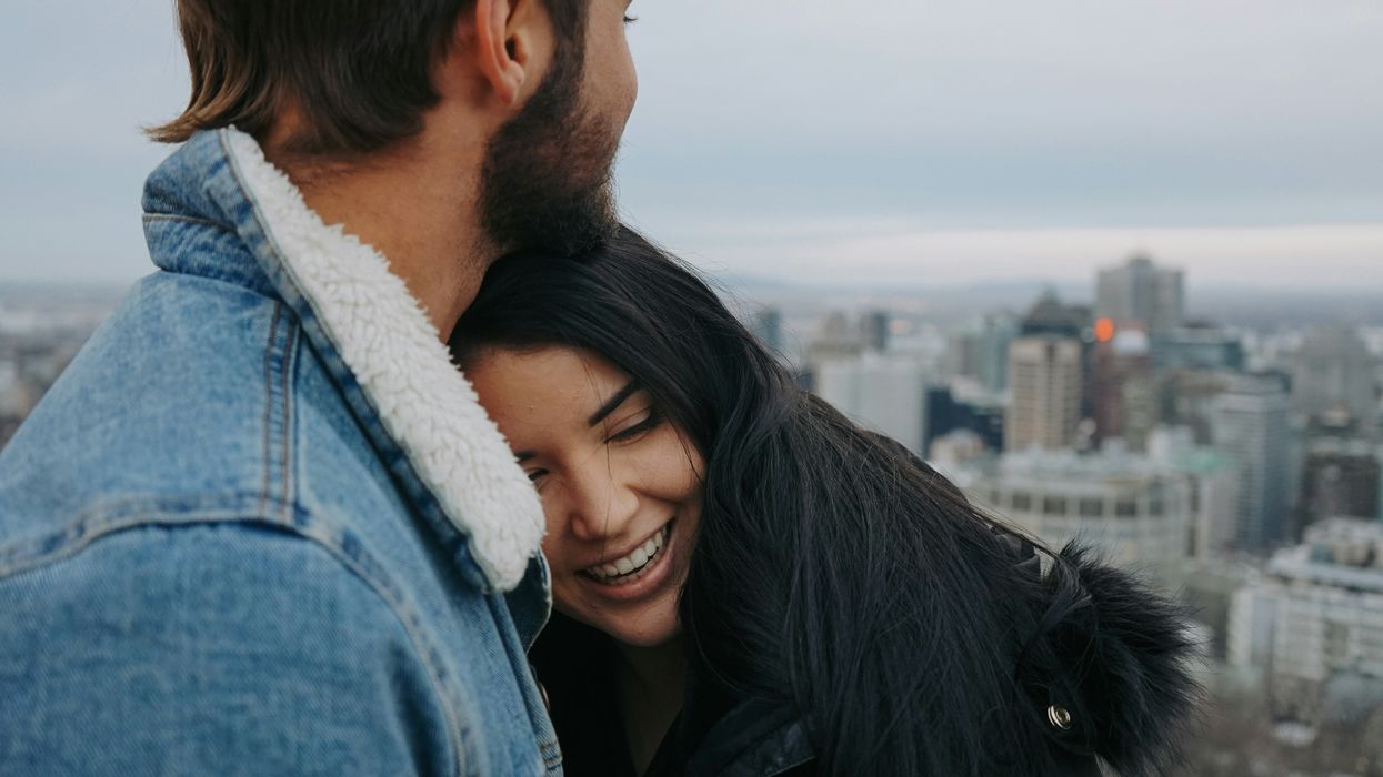 Two people cuddle on Mont Royal, overlooking the Montreal skyline.