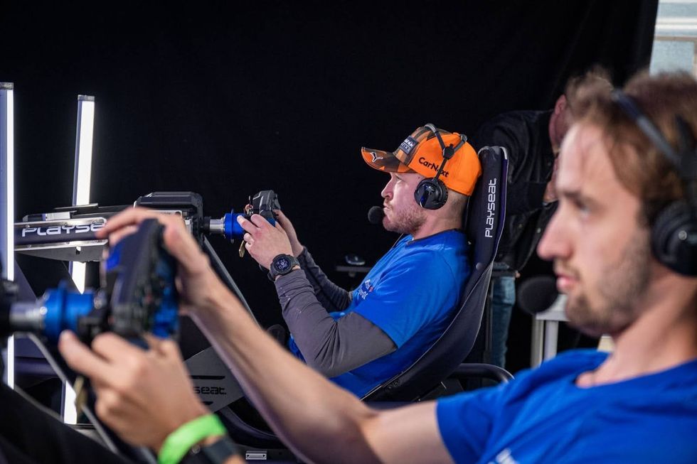 Two people driving racing simulators.
