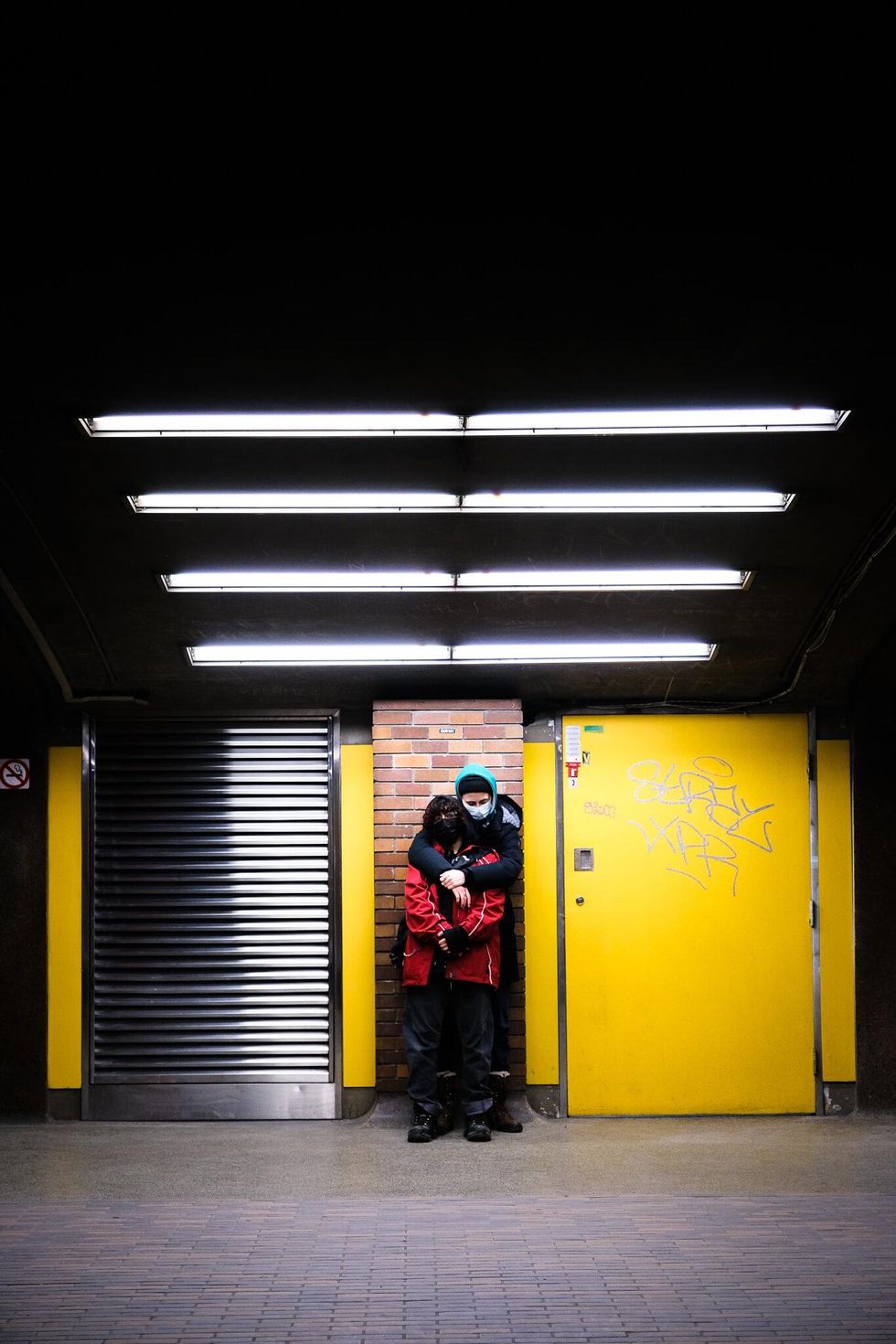 Two people embrace on a Montreal metro station platform.