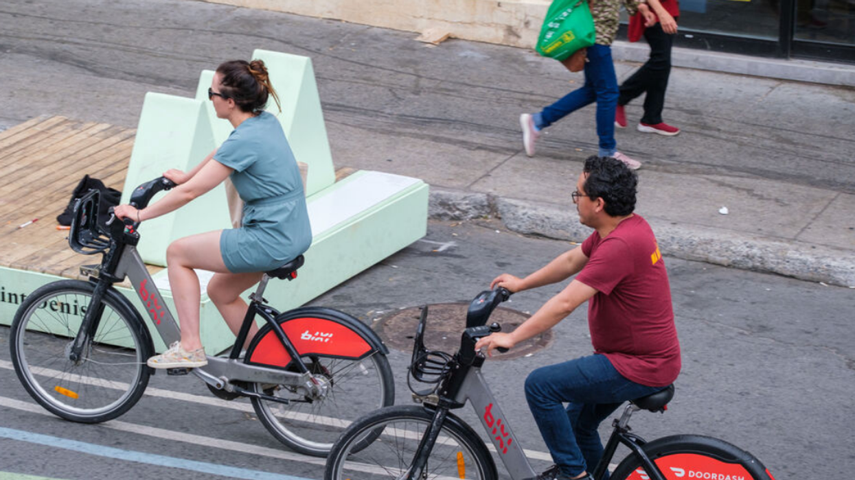 Two people ride BIXI bicycles through the streets of Montreal.