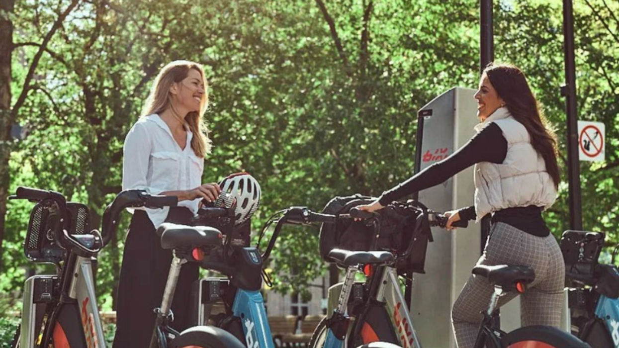 Two people standing at a Montreal BIXI shared bike station.