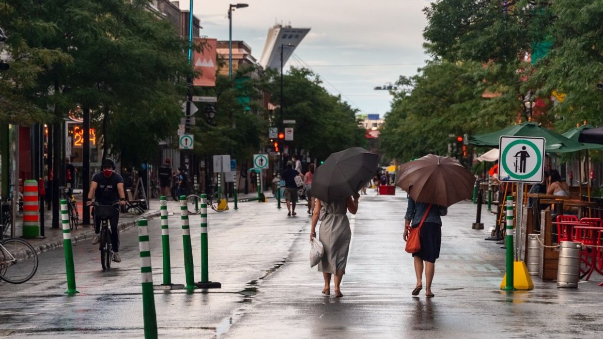 Two people walking down Mont-Royal Ave. in Montreal's Le-Plateau while it's raining.