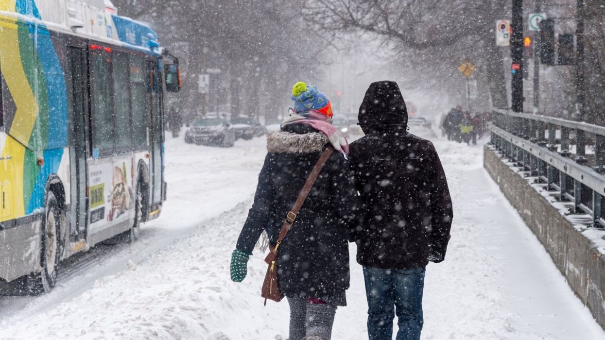 Two people walking on a Montreal sidewalk amidst a winter storm.