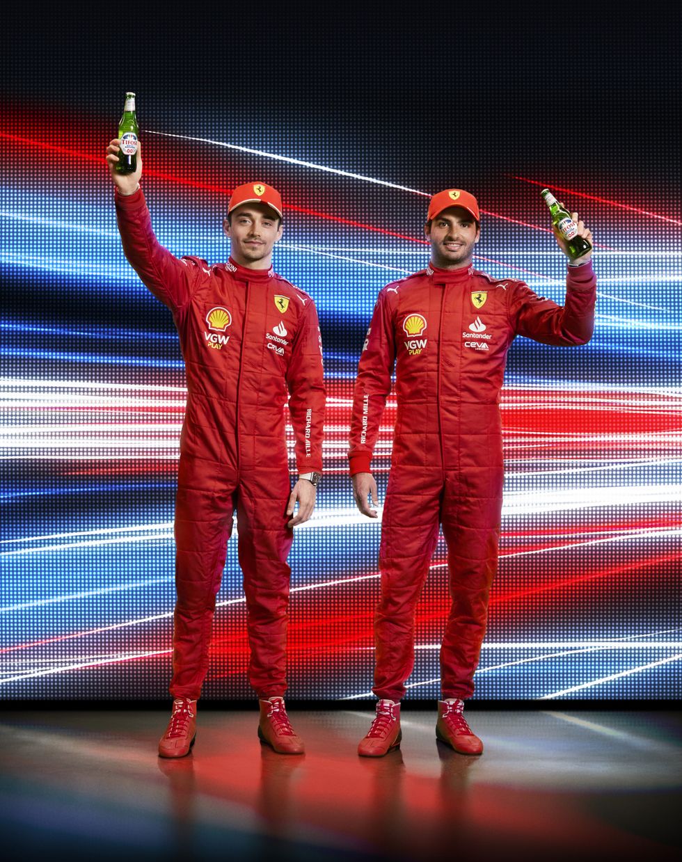 Two race car drivers, Ferrari team members Charles Leclerc and Carlos Sainz, holding Peroni Nastro Azzurro 0.0%.