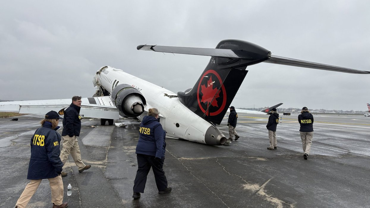 U.S. National Transportation Safety Board investigators examine the wreckage of an Air Canada plane crash.