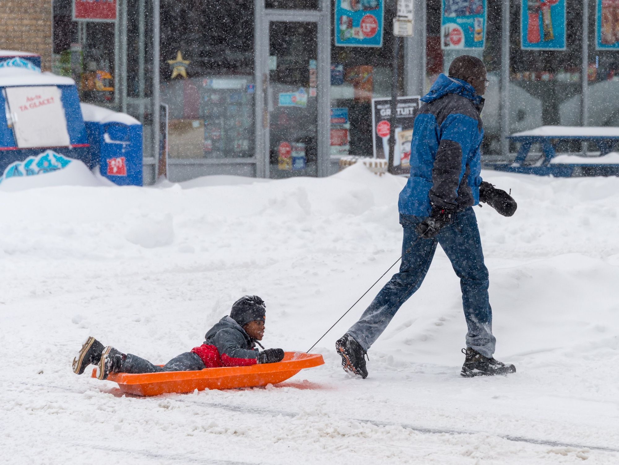 \u200bA father pulls his son on a sled in the snow.