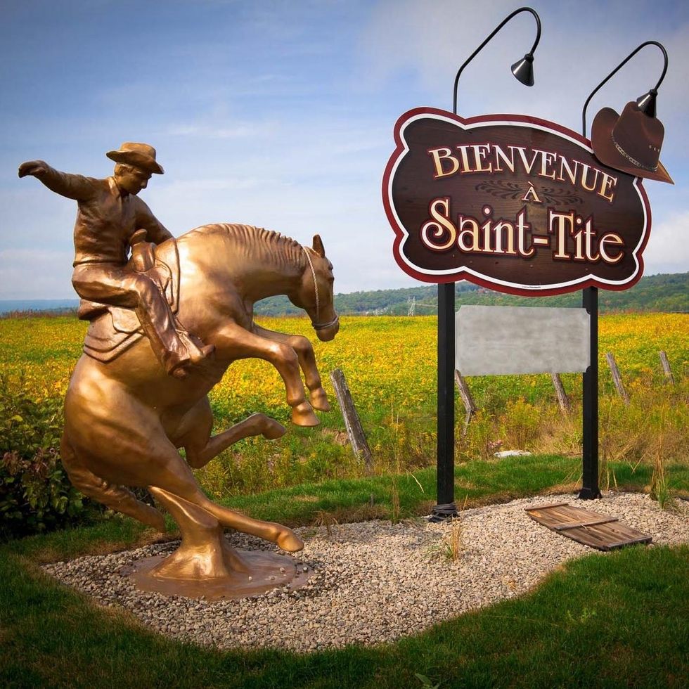 \u200bA golden statue of a cowboy on a bucking horse next to a welcome sign for Saint-Tite.