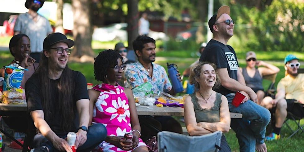 \u200bA group of people attending a comedy show in a park in Montreal.