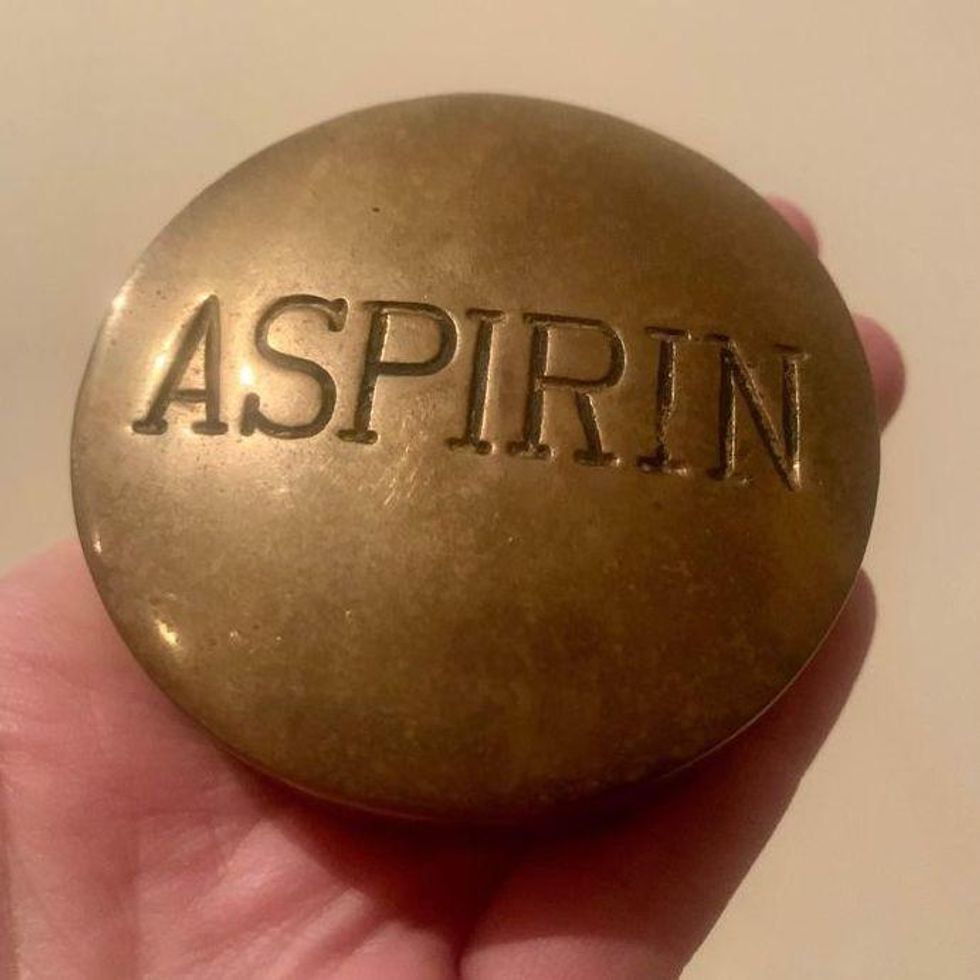 \u200bA large brass paperweight shaped like a pill with 'Aspirin' engraved on the front.