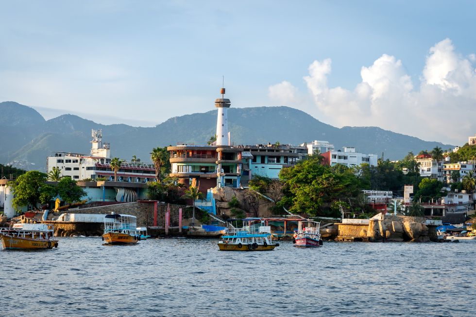 \u200bA lighthouse surrounded by small boats near Caleta Beach in Acapulco, Mexico.