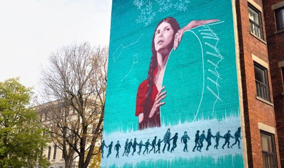 \u200bA mural of an Indigenous woman on a brick wall.