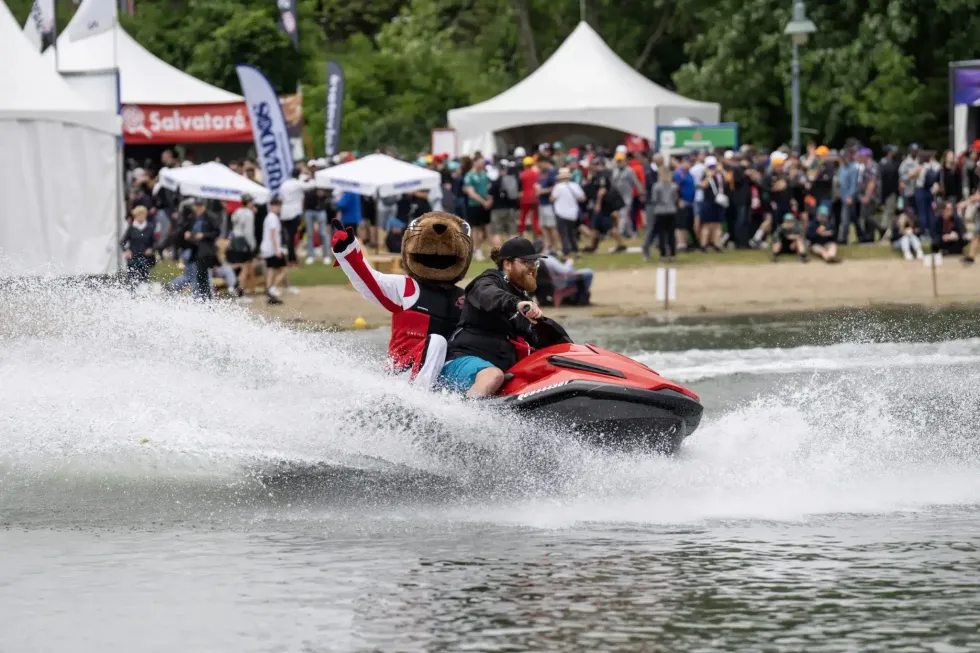 \u200bA person drives with a mascot on a Sea-Doo-style personal watercraft.