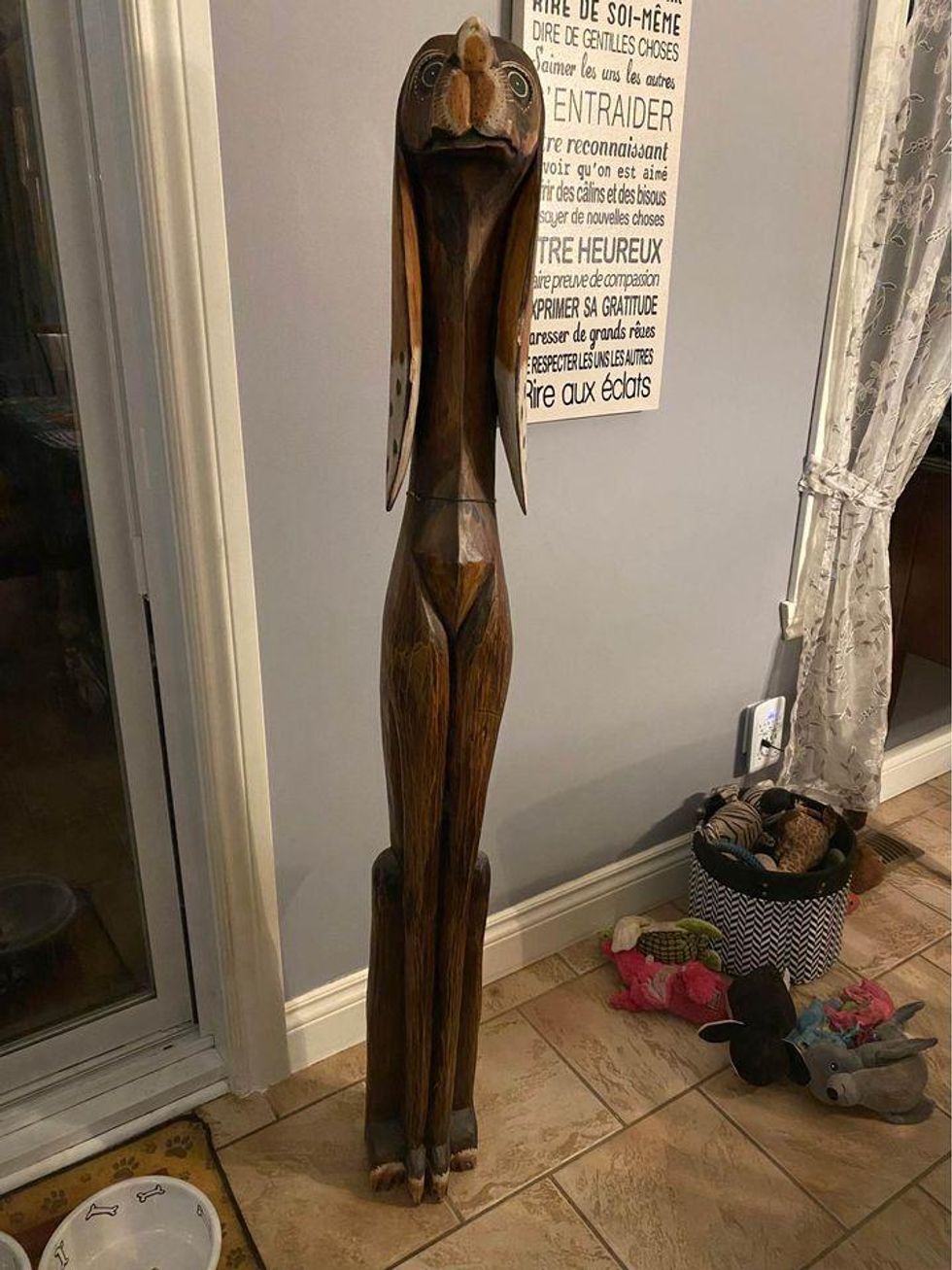 \u200bA startled and uncomfortable-looking elongated wooden dog statue.