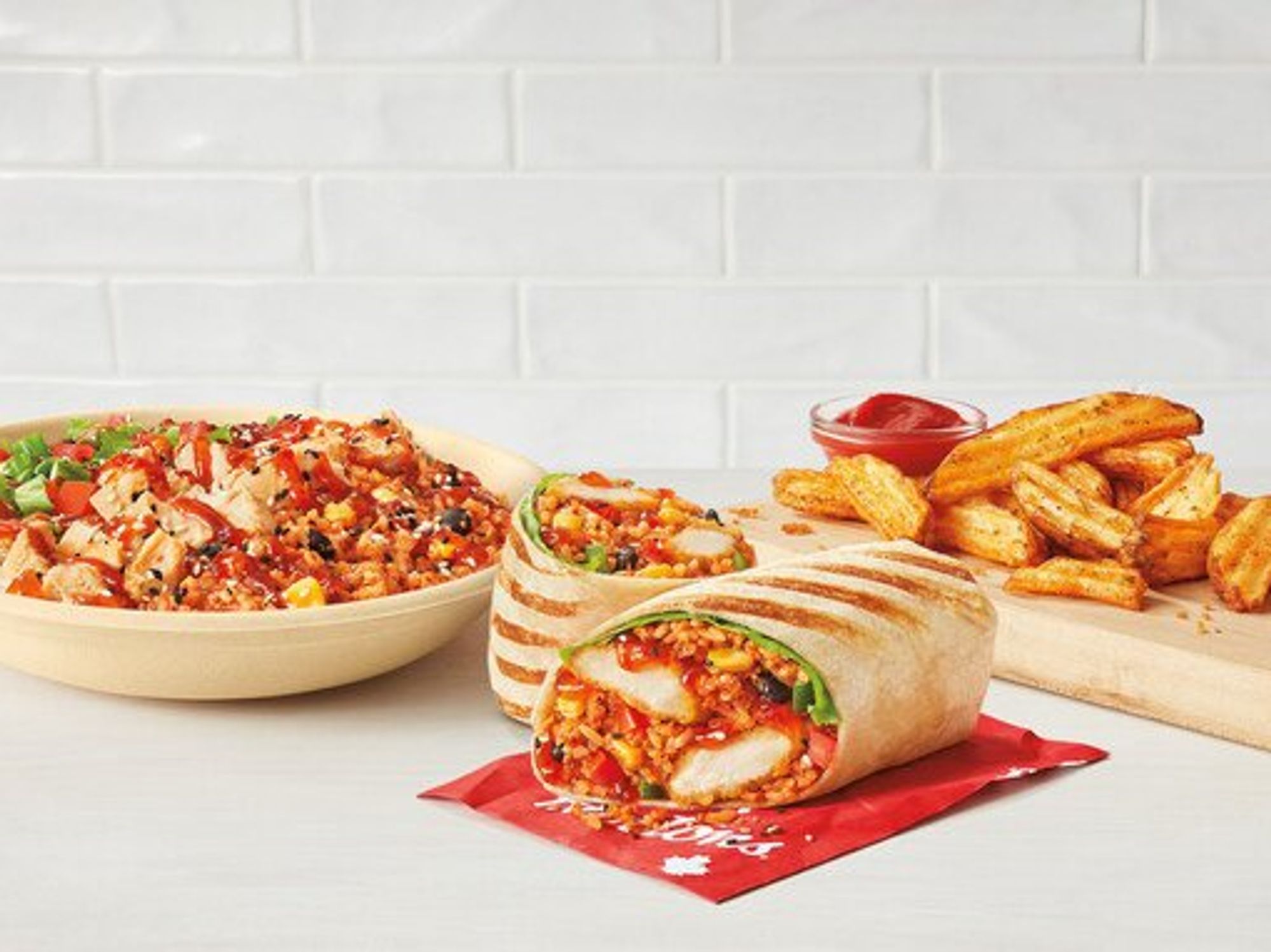 \u200bA Sweet Chili Chicken Loaded Wrap and Loaded Bowl, along with potato wedges with ketchup.