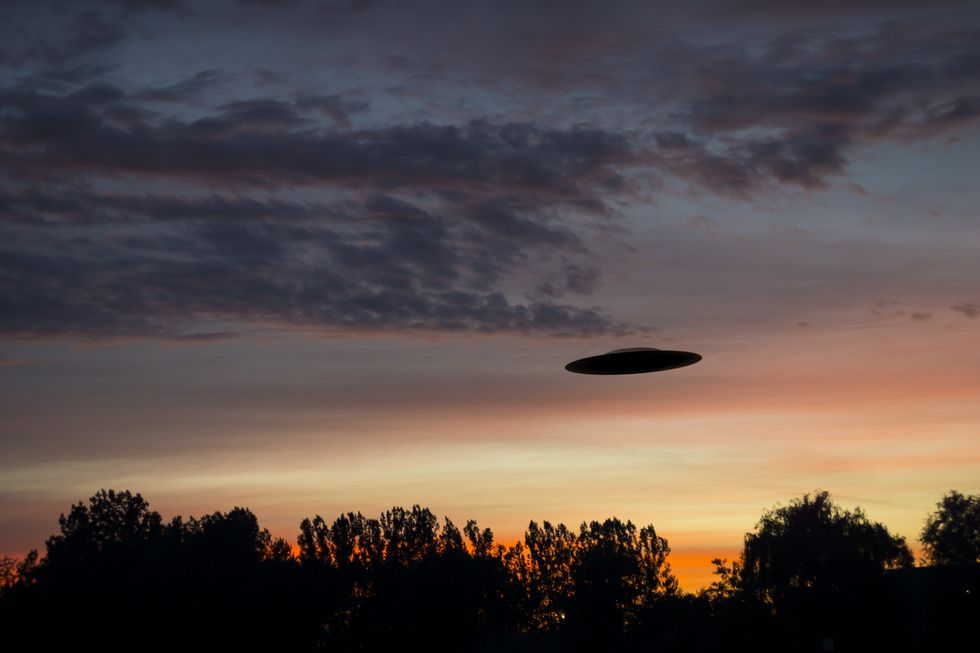\u200bA "UFO" flies over treetops at sundown.